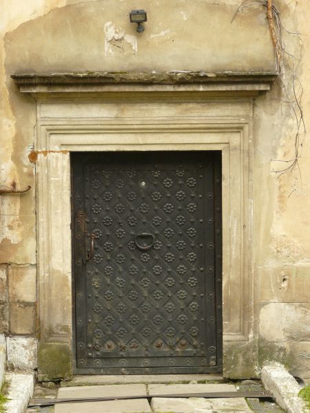 Large heavy metal doors with door knocker and engraved diamond and flower pattern.